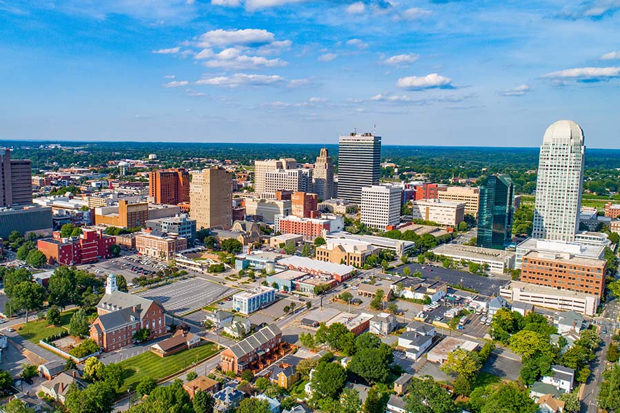 Contact - Aerial View of Downtown Winston-Salem, North Carolina Displaying Buildings and Trees on a Sunny Day