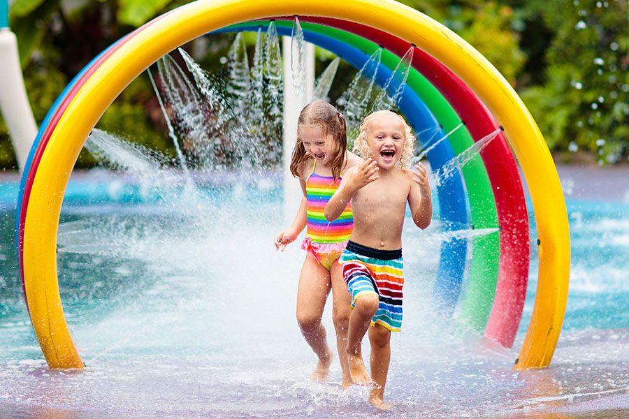 Personal Insurance - Happy Kids Running Through a Sprinkler at a Water Park